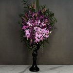 جام گل صورتی و بنفش گالری فلورانس با ترکیب زیبای ارکیده و لیلیوم، آرایش شده در یک vase مشکی شیک روی میز مرمر.