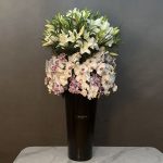 "گل آرایی ارکیده با اورینتال فلورانس، ترکیب شیک ارکیده و گل‌های اورینتال در vase مشکی."