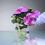 "دسته گل سازه‌ای با گل‌های ارکیده بنفش و سفید در طراحی مدرن، ایده‌آلی برای مراسم‌های شیک و خاص."