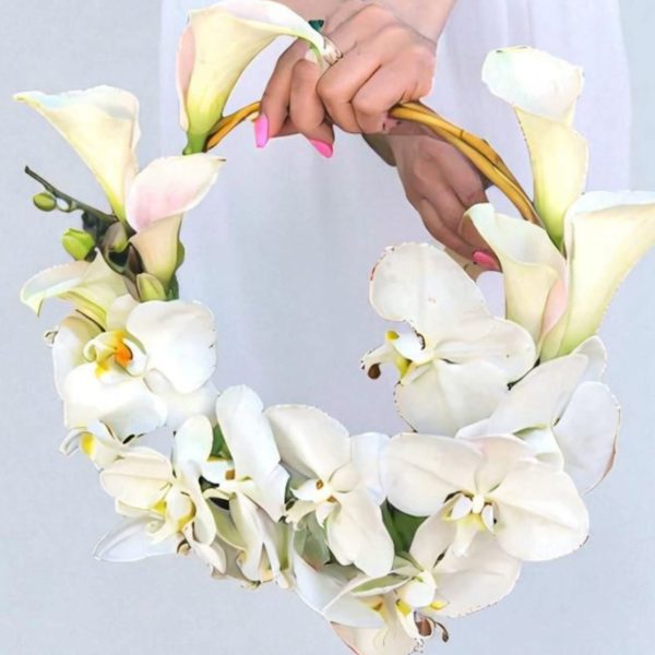 دسته گل عروس ارکیده حلقه ای طراحی شده با ارکیده‌های سفید و برگ‌های سبز طبیعی برای روز عروسی.